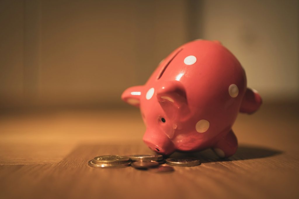 A red piggy bank beside a few coins