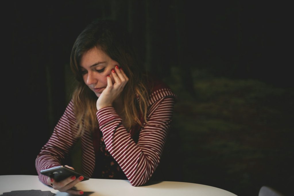 A woman at a table looking at her phone
